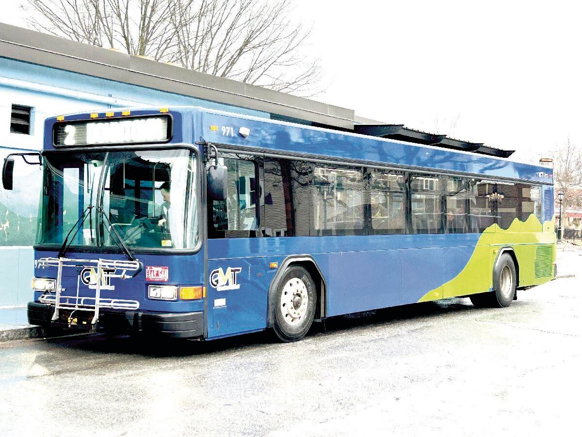 A blue public transit bus parked at a station with a green and yellow graphic on its side.