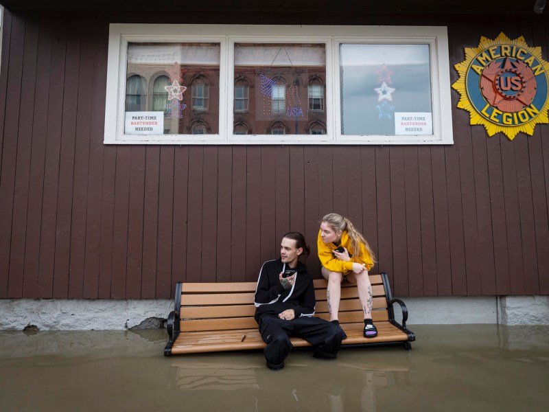 two people sitting on a bench in a flooded building.