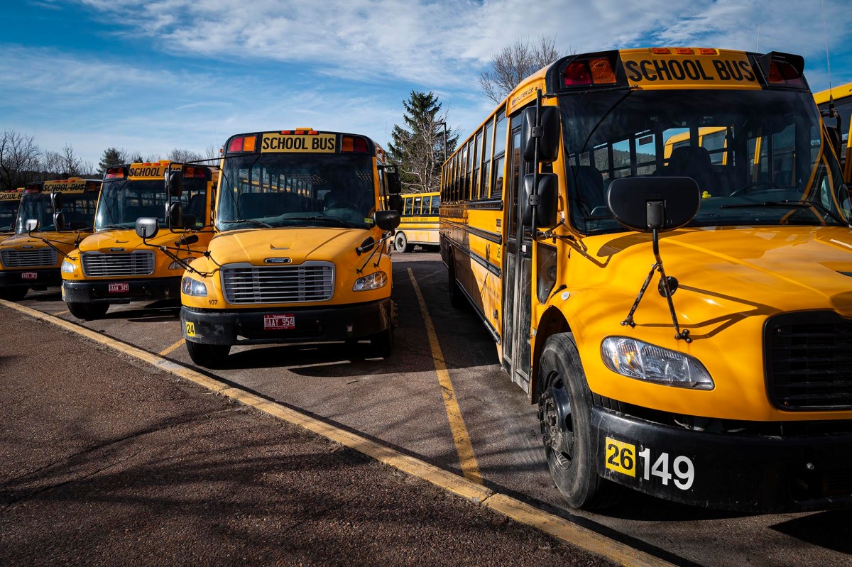 A row of yellow school buses parked in a parking lot.