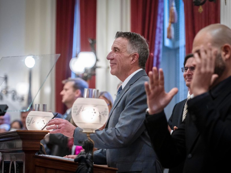 A man in a suit and tie is clapping at a podium.