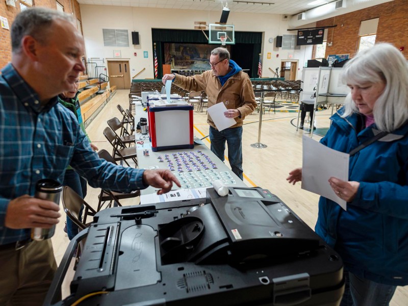 A man and a woman standing in front of a voting machine.
